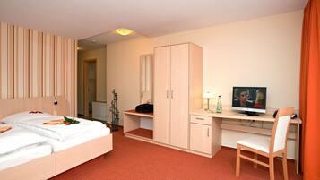 Ein Hotelzimmer mit Bett, Schreibtisch, Stuhl, Fernseher und Kleiderschrank.