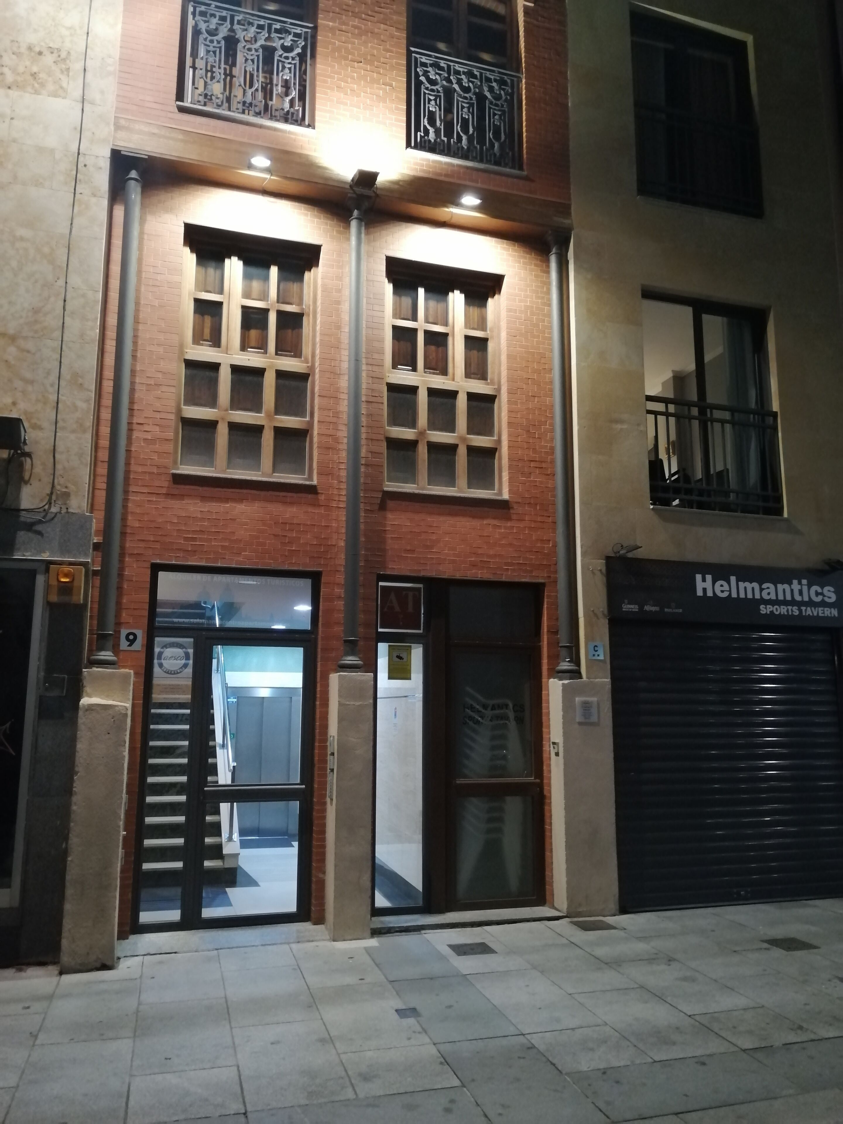A building with a brick facade, large windows, and a closed shop named "Helmantics Sports Tavern".