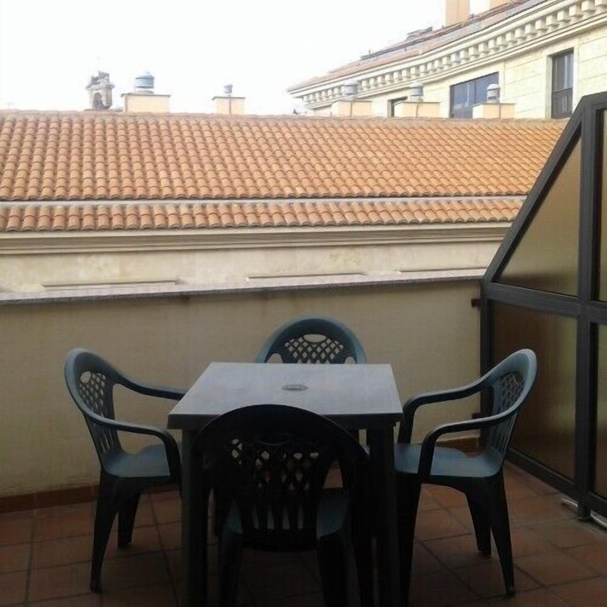 A small balcony with a tiled roof, a table, and four chairs.