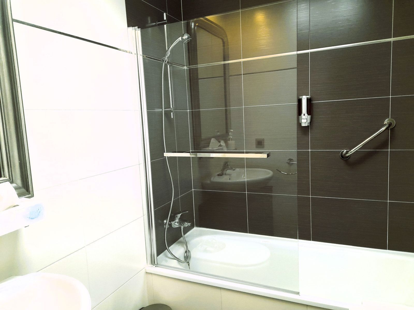 Un baño moderno con ducha acristalada, lavamanos blanco y ducha de mano.