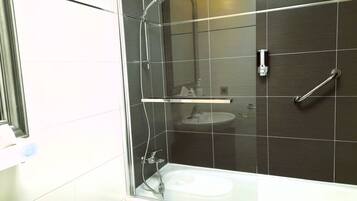 Un baño moderno con ducha acristalada, lavamanos blanco y ducha de mano.