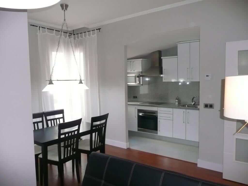 A compact living space with a dining area, kitchenette, and a sofa.