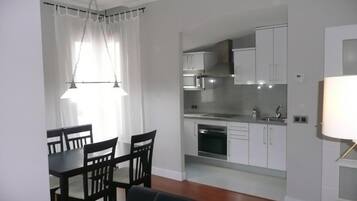 A compact living space with a dining area, kitchenette, and a sofa.