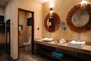 Un baño moderno con tocador de madera, dos lavamanos y un espejo grande con marco circular.