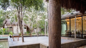 A resort courtyard with a pool, wooden benches, and a dining area with glass walls. - Aldea Coba an Escape Resort (Coba)