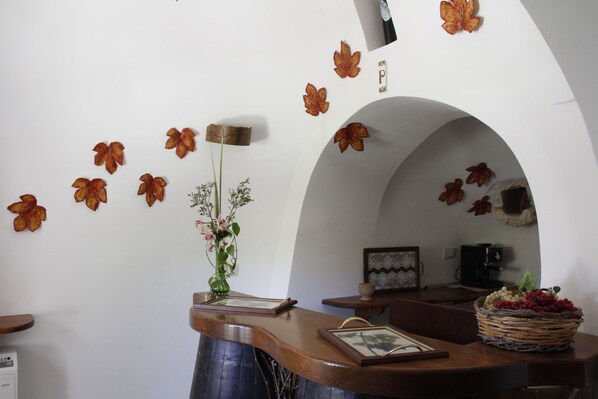 A room with a curved wooden desk, a vase with flowers, and a wall decorated with autumn leaves. - Relais Il Palmento (Locorotondo)