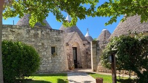 A stone building with a central archway, surrounded by a well-maintained lawn and trees. - Relais Il Palmento (Locorotondo)