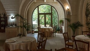 A restaurant with arched ceilings, round tables, and chairs, featuring a view of greenery through large windows. - Relais Il Palmento (Locorotondo)