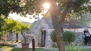 A stone building with a tiled roof, a paved pathway, and potted plants. - Relais Il Palmento (Locorotondo)