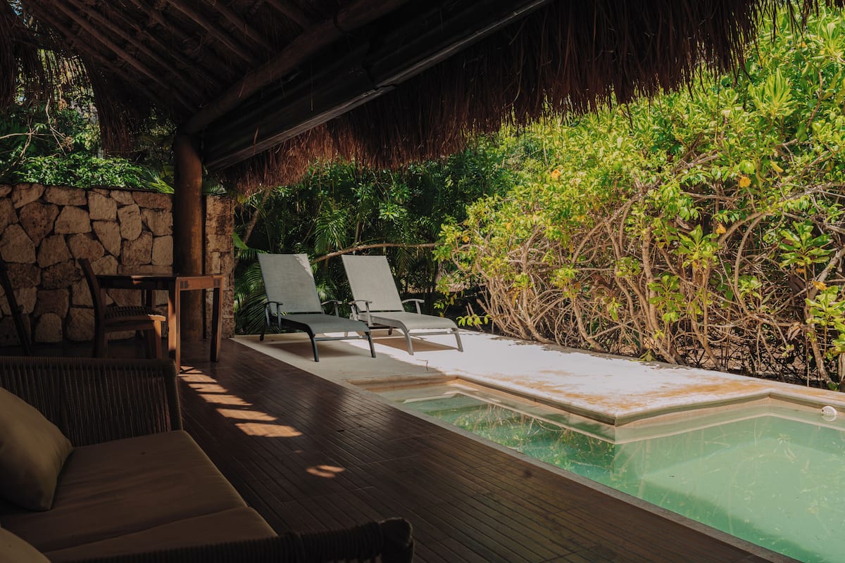 A poolside area with lounge chairs and a stone wall.