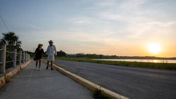 A paved walkway beside a road with a sunset in the background.