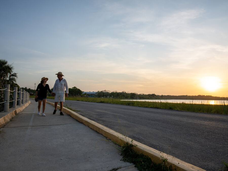 A paved walkway beside a road with a sunset in the background.