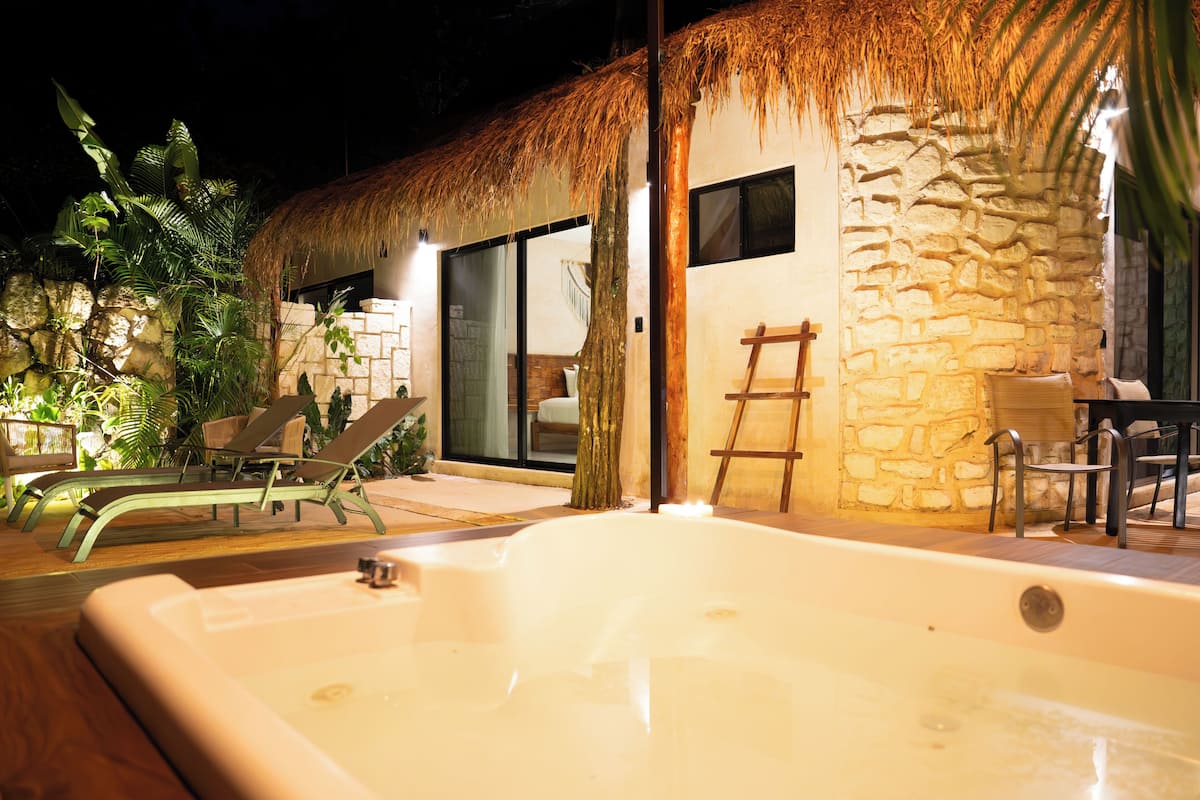 A spa area with a hot tub, lounge chairs, and a stone wall.