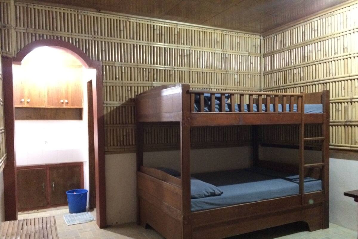 A bunk bed room with a wooden bunk bed, a small desk, and a wardrobe.