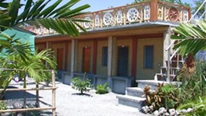 Un bâtiment doté d’une façade recouverte de tuiles, d’un porche et d’une cour intérieure en gravier.