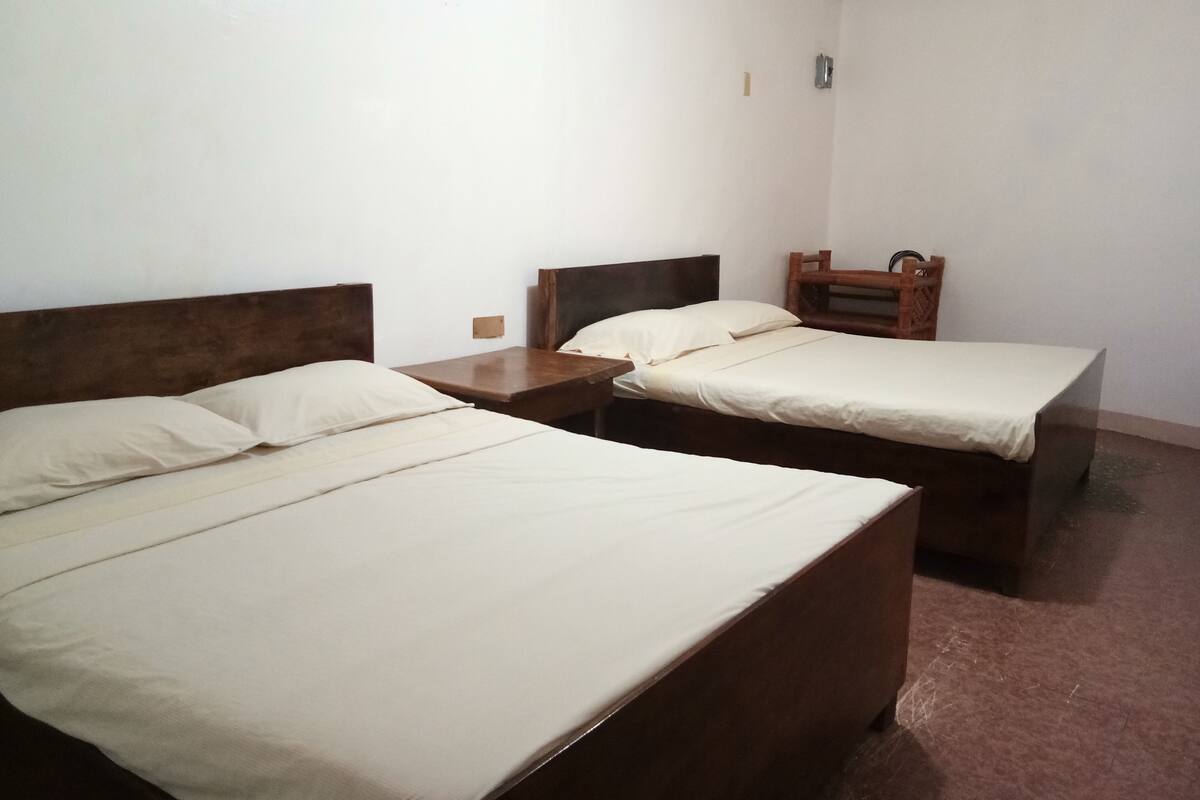 A room with two single beds, wooden headboards, and a small wooden table.