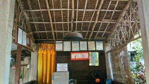 Un espace d’accueil doté d’un plafond en bambou, d’un comptoir d’enregistrement et d’un panneau d’information.