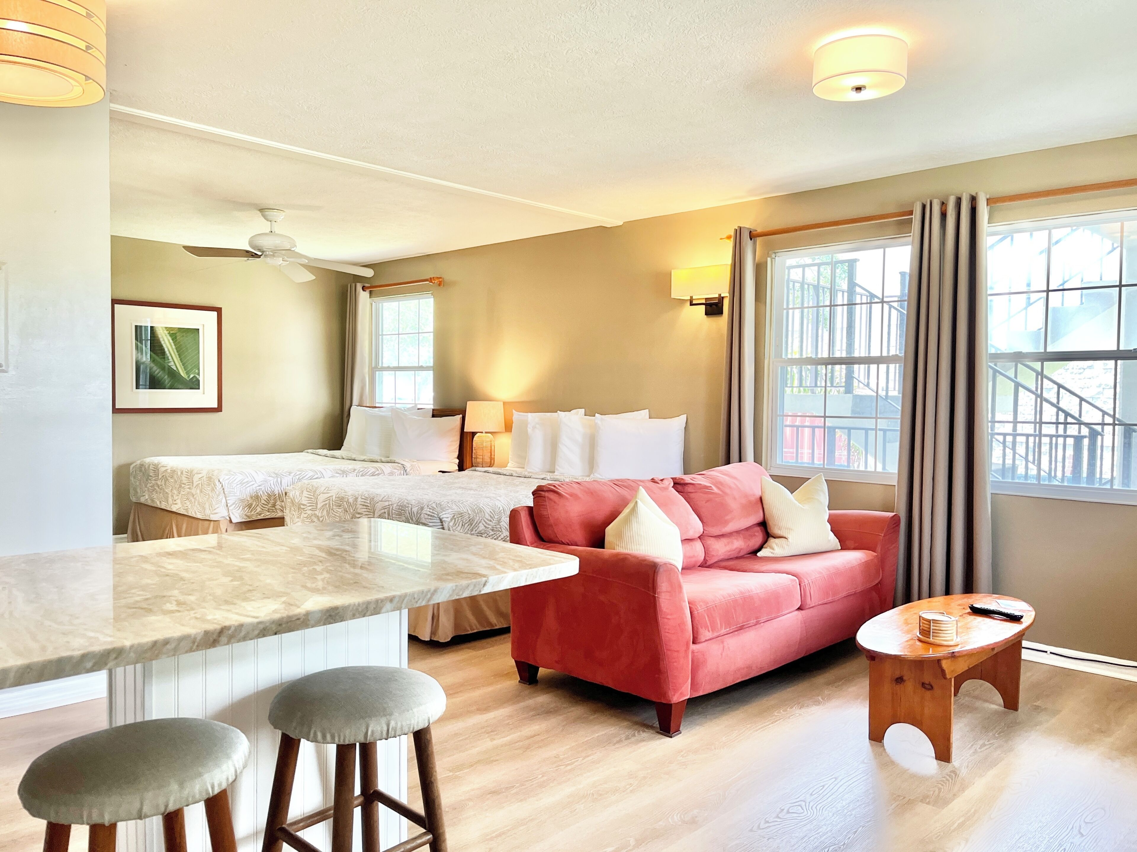 Een hotelkamer met een bed, een rode bank, een klein houten tafeltje en een marmeren aanrechtblad.