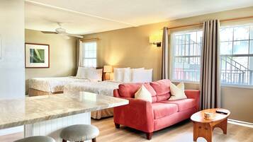 Une chambre d’hôtel avec un lit, un canapé rouge, une petite table en bois et un comptoir en marbre.