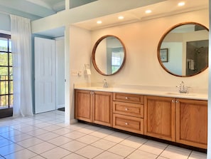 A modern bathroom with a large vanity, two round mirrors, and a tiled floor. - Davis House Inn (Sebastian)