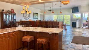 A spacious kitchen with a large island, wooden cabinets, and a dining area with chairs. - Davis House Inn (Sebastian)