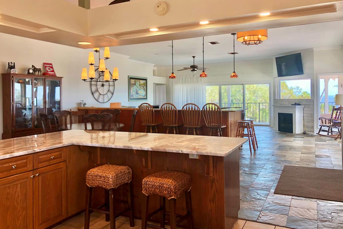 A spacious kitchen with a large island, wooden cabinets, and a dining area with chairs.