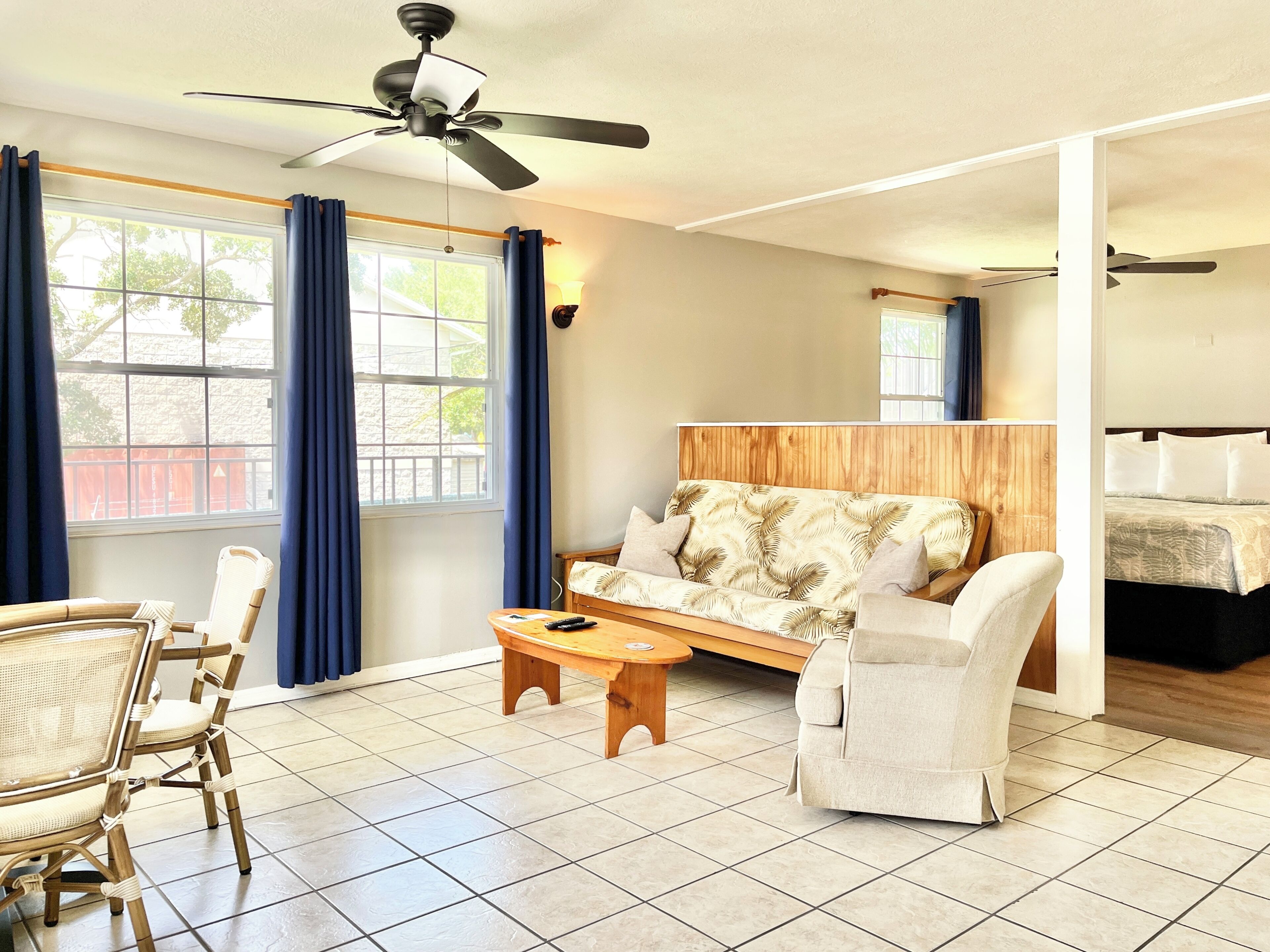 Une pièce comprenant un lit, un canapé, une chaise, une petite table et un ventilateur de plafond.