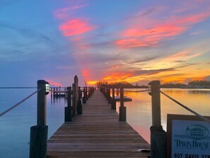 A wooden pier extending into calm water with a sunset in the background. A sign for 'Davis House' is visible on the right. - Davis House Inn (Sebastian)