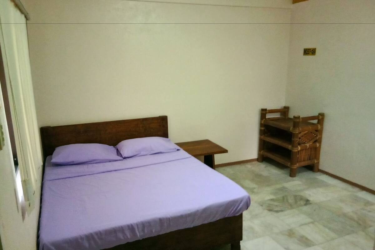 A bedroom with a bed, a small wooden nightstand, and a wooden chair.