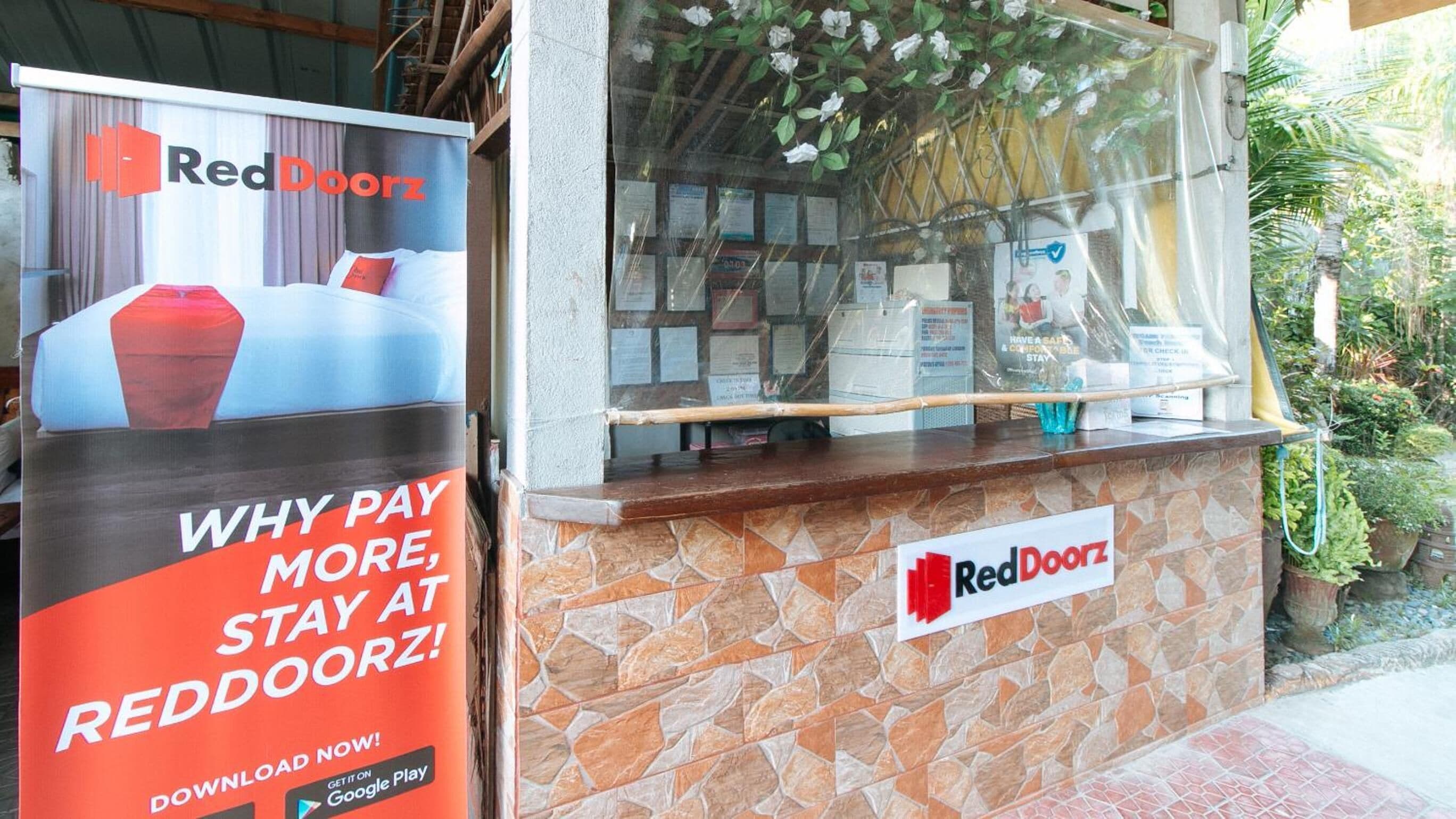 En RedDoorz kiosk med stenvæg og glasudstilling.