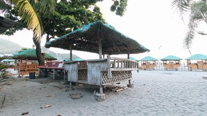 A beach with wooden structures, including a small hut and several thatched-roof shelters. - Megan's Paradisio Beach Resort (San Antonio)