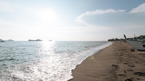 A beach with a boat on the sand and calm water. - Megan's Paradisio Beach Resort (San Antonio)