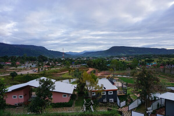 A residential area with houses, a small body of water, and hills in the background.