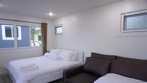 A bedroom with a bed, a brown sofa, and a window. - Phu Sumphao Valley (Phu Ruea)