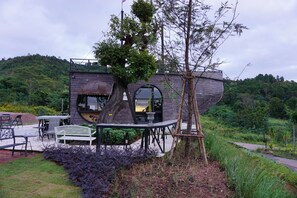 Una casa con una estructura inusual en forma de barco, mobiliario exterior y un jardín.