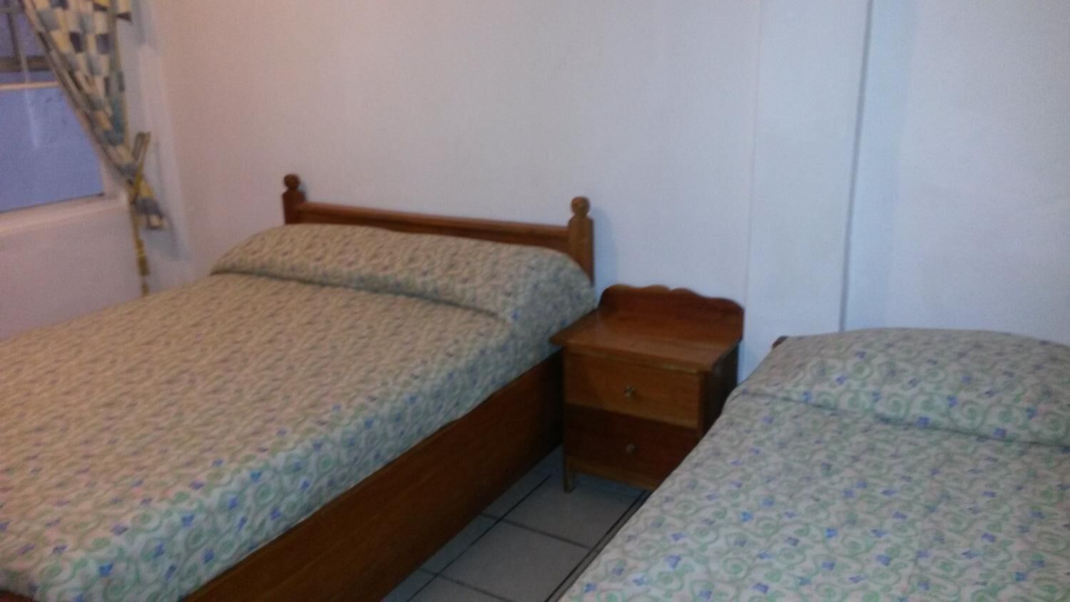 Une petite chambre avec un lit simple, une tête de lit en bois et une table de chevet.