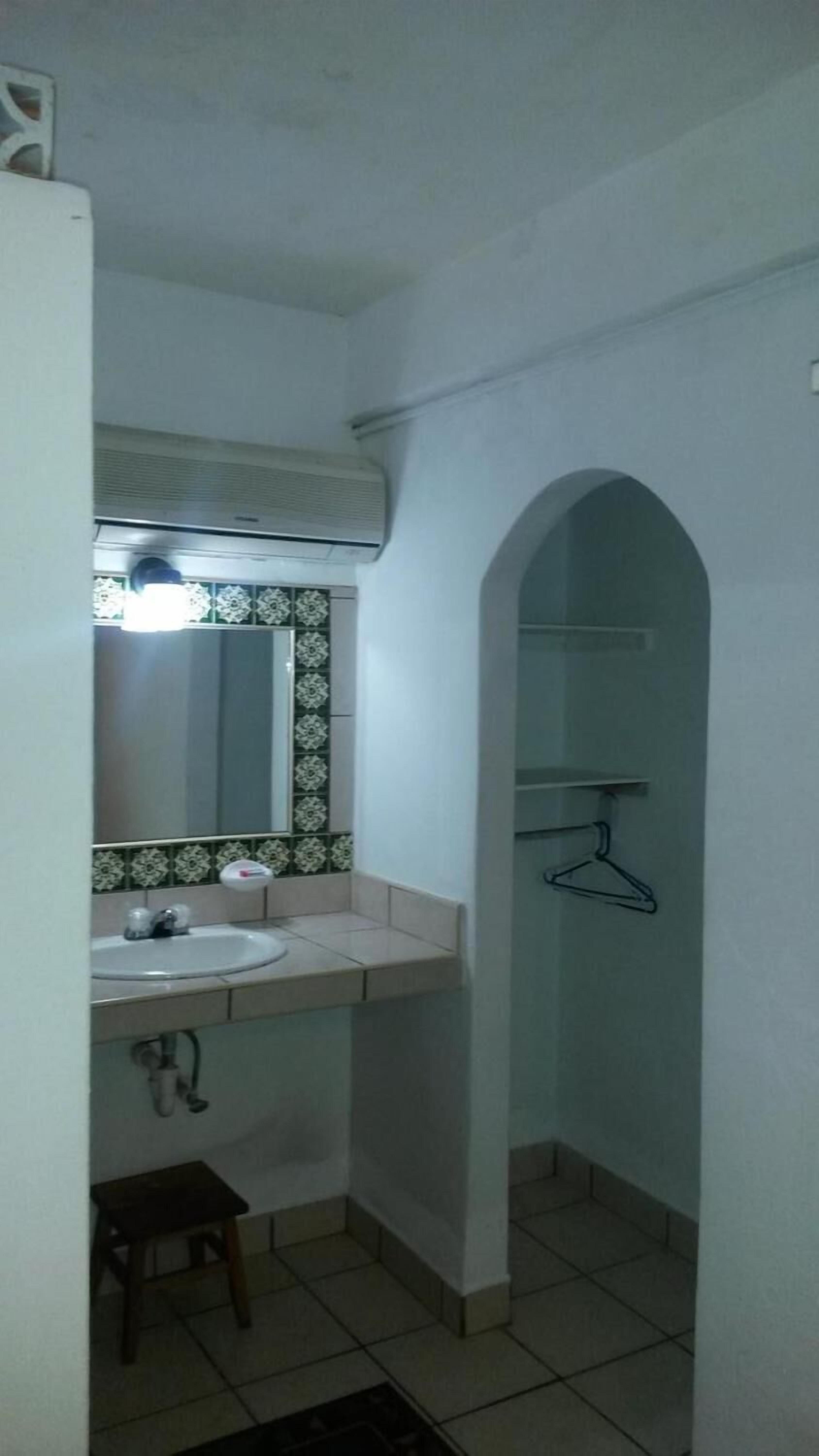 Un baño pequeño con lavamanos, espejo y perchero.