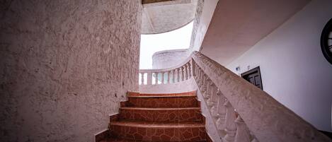 A spiral staircase with stone steps and white balustrades, leading to a landing with a door marked "27".