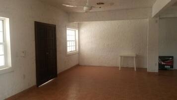 Una habitación con piso de baldosas, ventilador de techo, una ventana y una puerta.