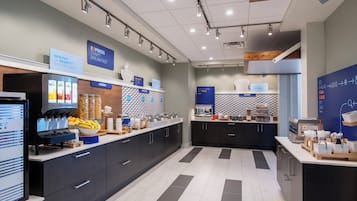 A modern breakfast area with a self-serve station, cereal, hot food, and bakery options.