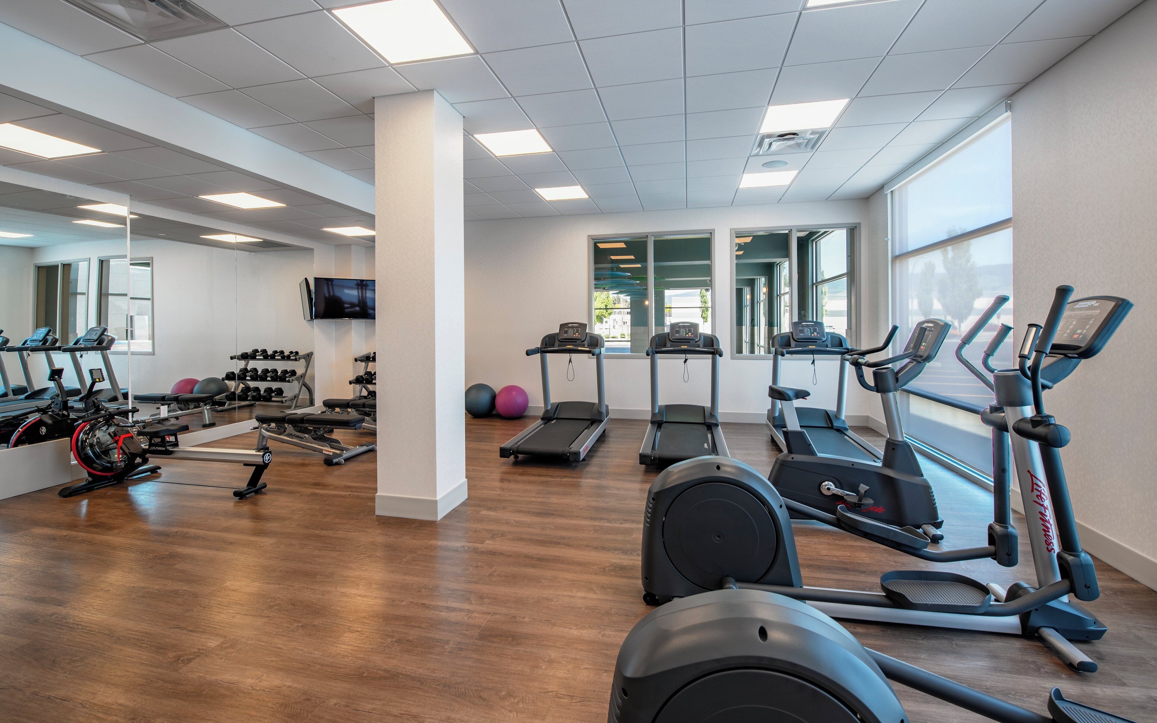 A gym with treadmills, elliptical machines, and weightlifting equipment.
