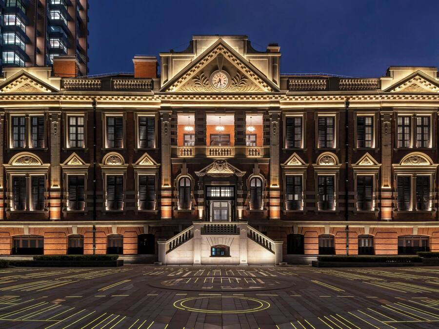 A grand, historic building with a symmetrical facade, large windows, and a central entrance with a staircase.