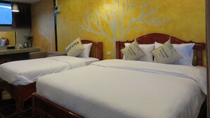 Una habitación de hotel con dos camas, cada una con ropa de cama blanca y almohadas con el rótulo "SHIPSTER". Un mural grande con un árbol adorna la pared, y hay una ventana con vistas al cielo.