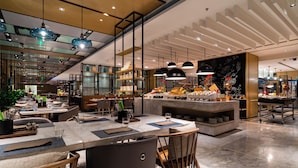 A modern restaurant with a central island, multiple dining tables, and hanging pendant lights. - Courtyard by Marriott Shunde Longjiang (Foshan)