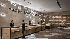 A modern reception area with a long counter, a receptionist, and a guest. - Courtyard by Marriott Shunde Longjiang (Foshan)