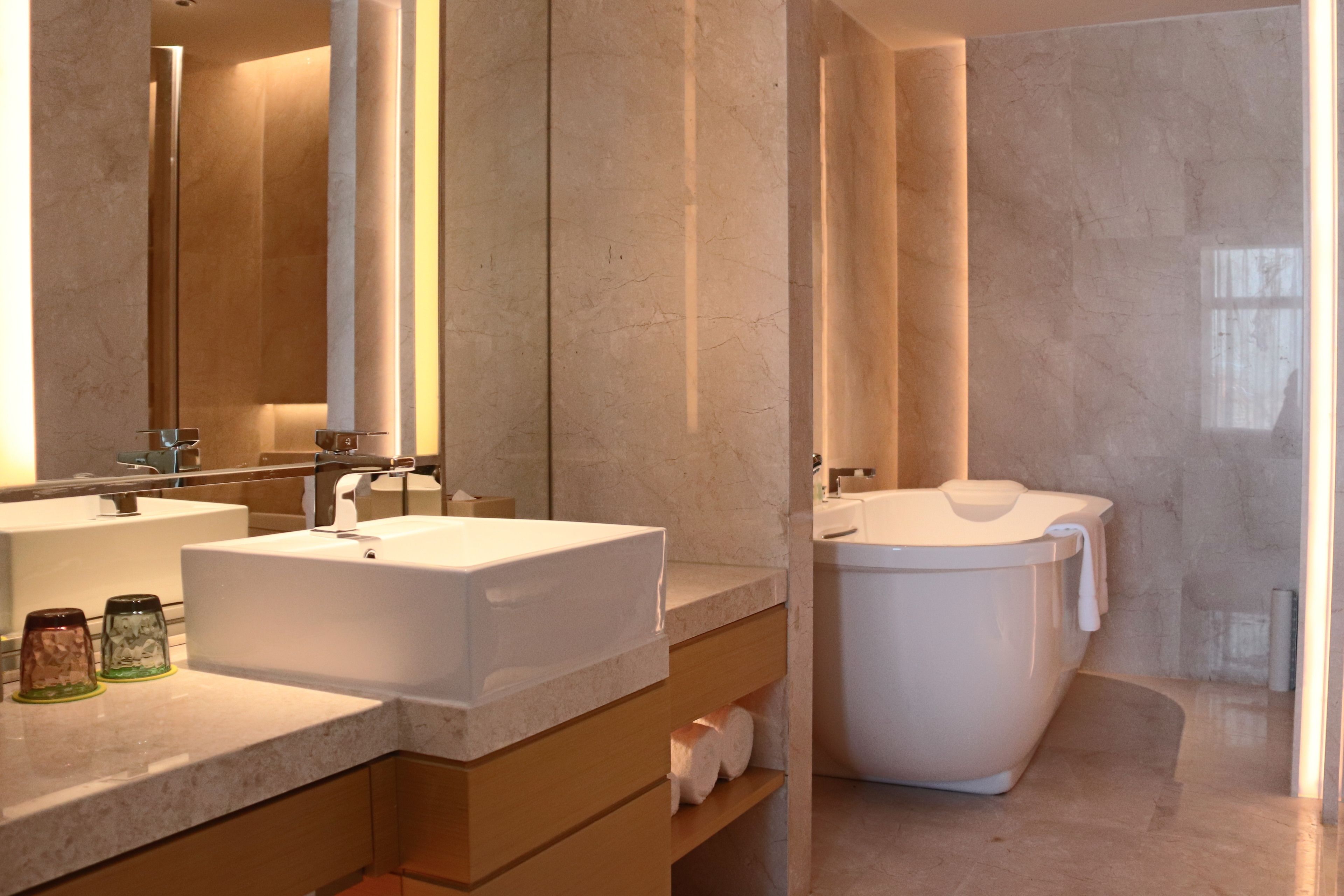 A modern bathroom with a large bathtub, two sinks, and a mirror.
