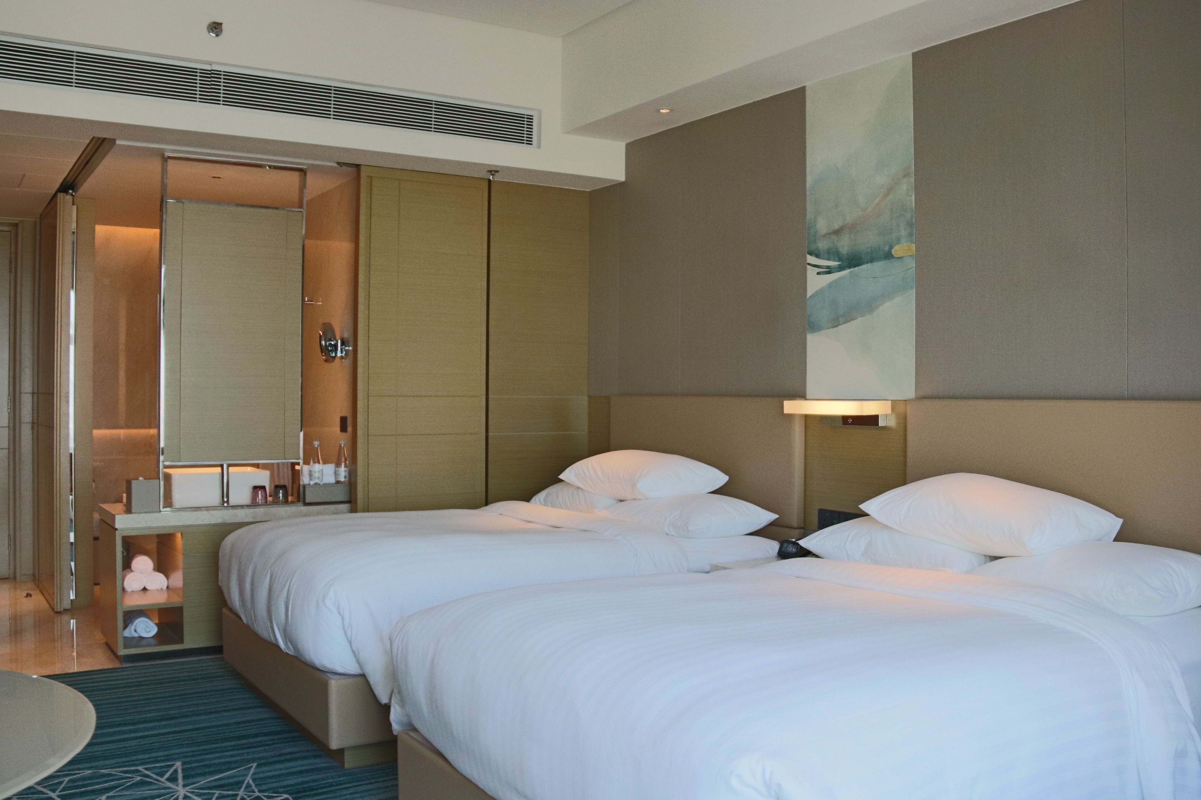 Une chambre d’hôtel avec deux lits, une table de chevet, un miroir et un tableau au mur.