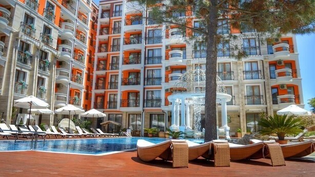 A multi-story hotel with balconies, a swimming pool, and lounge chairs. - Harmony Palace (Burgas)