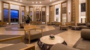 Un vestíbulo amplio con zona de estar central, una planta grande en maceta y paneles de madera tradicionales.