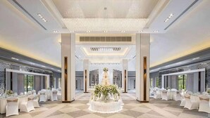 Un amplio salón de banquetes con un arreglo floral central, techos altos y una distribución simétrica.